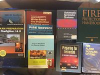 Books on fire fighting, fire protection, and emergency management arranged on a surface.