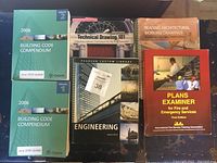 Photo showing six textbooks/manuals including two green Ontario Building Code Compendiums, Technical Drawing 101, Engineering Mason Custom Library, Reading Architectural Working Drawings, and Plans Examiner.