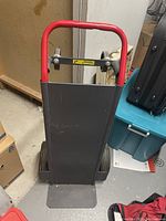 Front view of cargo cart showing red handle, gray flat cargo base, and two large back tires.
