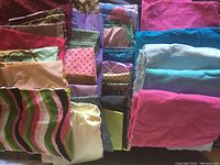 Photo shows multiple folded fabric pieces with various solid and printed patterns in different colors.