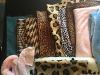 Photo showing animal print fabrics with various textures including checkered, leopard and other patterns, alongside pink and blue plush fabrics.
