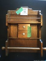 Wooden vintage spice rack front view showing two small drawers with white knobs, spice shelf above, and paper towel holder below.