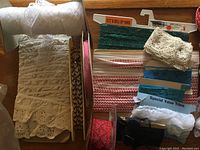Photo showing multiple vintage trims including lace, braid, and ribbon on cardboard spools and loose pieces.