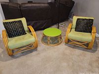 Full set with two bamboo chairs featuring green cushions and black/gold pillows alongside matching round bamboo coffee table with green top