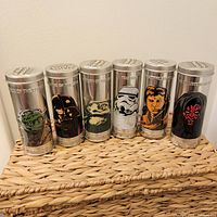 Seven metal collectible tins featuring Star Wars characters: Yoda, Darth Vader, Jabba the Hutt, Stormtrooper, Han Solo, another character (possibly Luke Skywalker), and Darth Maul. Each tin has embossed text and colorful character artwork.