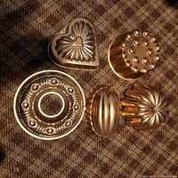 Top view of five copper molds on carpet background showing heart, round, flower, oval and donut shapes