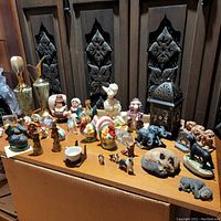 Overall view of assorted vintage figurines including animals, decorative pitchers, and salt and pepper shakers on wooden surface.