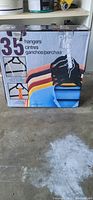 Box showing the lot of 35 plastic clothes hangers in assorted colors including black, white, yellow, and orange.