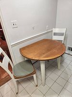 Kitchen table with two chairs positioned in a tiled floor room showing size and style