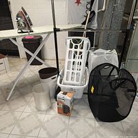 Lot contents shown together including laundry baskets, ironing board, iron, space heater