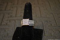 Front view of the silver CZ ring on a black ring holder showing the square cluster top and three rows of stones on the band.