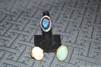 Front view of three rings on display stand and surface, showing oval stones and colors