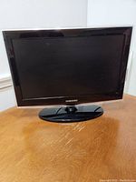 Front view of Samsung 19 inch LCD television on a wooden surface, showing screen and bezel.