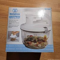 Front view of the Westinghouse SaladXpress box showing the product in clear plastic bowl with chopped vegetables and the main white electric lid unit.