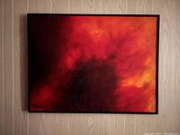 Frontal view of the framed abstract painting showing fiery reds, oranges, and blacks with artist signature on bottom left.