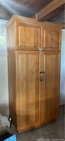 Tall free-standing wooden pantry cabinet with two upper and two lower doors on kitchen floor