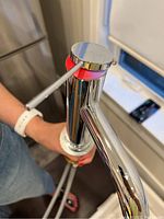 Photo of the top control lever and chrome faucet body held upright showing red and pink protective color marking under the lever.