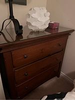 Photo shows a brown wooden three drawer dresser with round metal knobs and clear glass top. Dresser dimensions approximately 40 x 20 x 36 inches.