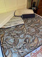Twin-size bed with one reversible duvet cover set displayed, showing paisley and stripe patterns, pillow shams, and decorative pillows.