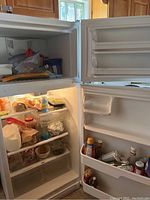 Opened view of refrigerator and freezer compartments showing contents and shelving.