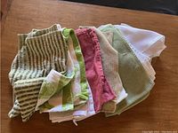 Folded assorted dish towels in various colors and patterns on brown surface, showing texture and color variety.