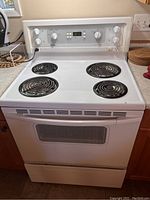 Front view of Kenmore white electric stove showing four coil burners and control panel with knobs and digital display.