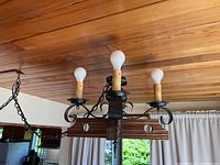 Wooden chandelier hanging from ceiling with three candle-style bulbs and metal arms