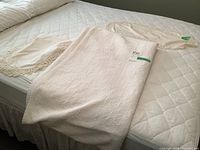 Quilted comforter, bed skirt, and doilies displayed on a bed