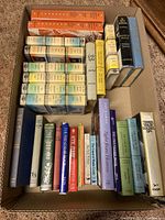 Overhead photo of vintage hardcover fiction books packed in a box including several series and individual titles, shows condition and variety