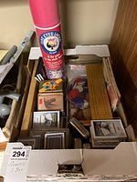 Box with assorted souvenir playing cards, game chips, cribbage board, and One Eyed Jacks game tube visible