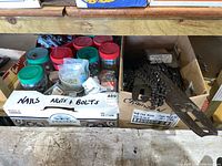 Box with labeled containers of nails, nuts, and bolts on a wooden shelf.