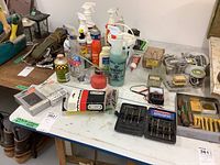 View of household cleaning products, hardware, drill bits, and tools arranged on tables
