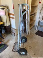 Side view of metal hand truck with two large pneumatic tires, showing chipped paint and used condition