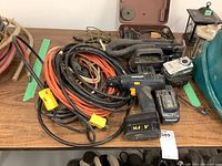 Power tools including cordless drills, extension cords, snake lights and camera laid out on table