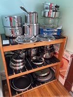 Wooden rack displaying full assortment of stainless cookware and boxed baking stone