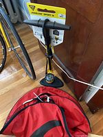Full view of the assembled Topeak JoeBlow Sport III bike pump with handle, hose, and pressure gauge, alongside red Fulcrum tire bags on floor.