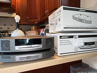 Wave Music System main unit and 4-disc CD changer stacked side by side with original Bose boxes behind