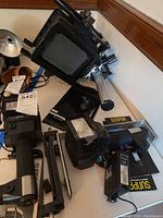 Overview of lot showing two Sunpak flash units, Vivitar flash, Toyo View camera and accessories on tabletop.