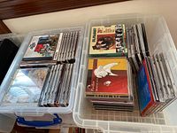 Two plastic storage bins filled with assorted music CDs in jewel cases, showing artist names such as The Byrds, The Clash, and Talking Heads.