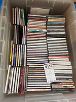 Large bin filled with multiple rows of CDs, showing many titles and covers stacked upright.