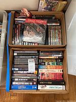 Boxes of assorted DVDs and VHS tapes laid out, showing titles including Star Trek, Gone With The Wind, Columbo, and various martial arts and TV series VHS and DVDs.