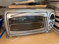 Front view of the silver Euro-Pro digital convection oven with glass door, digital control panel on the side, power cord visible, and the oven interior with rack and tray.