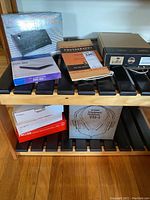 Shelf view showing multiple boxed electronics and books including the Hi-Tech echo chamber, Kodak Handbook, Yamaha headphones, Kindle, and others.