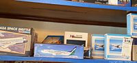 Shelf view showing NASA Space Shuttle box, generic aircraft kit in green tail livery, two blue-trimmed Passenger Plane Model boxes