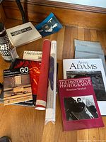 Photography-themed books and posters on floor including various titles and rolled posters.