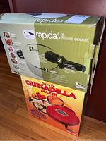 Rapida 4qt pressure cooker and Santa Fe quesadilla maker both in original boxes stacked.