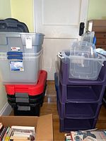 Stacked plastic storage bins and drawer units in grey, black, red, and purple colors near a door and floor, showing size and colors.