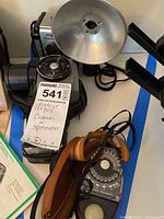 Argus 75 camera with attached flash and Norwood Director light meter alongside carrying case and leather strap.