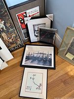 Five framed wall art pieces arranged against wall on floor showing various artistic styles and frame types.