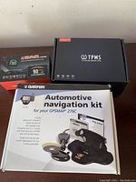 Three items shown: Garmin automotive navigation kit box, TPMS tire pressure monitoring system box, and windshield speed monitor box